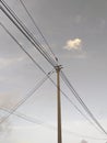 Wooden pole and electrical wiring under tropical gray sky. Chaos of telephone cables. Detail of Caribbean and tropical