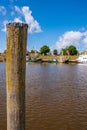 Wooden pole in the left half of the picture, trawler and crab boats in the harbor of Greetsiel out of focus in the background