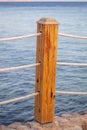 Wooden pole of a rope fence near the sea Royalty Free Stock Photo