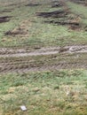 Wooden poles wet from rain on the grass surface with tyre traces in wet soil