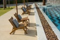 Wooden pool chair in the edge of the swimming pool with shade of light at Summer Time