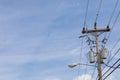 Wooden power pole with mixed power and fiber optics cable wires, street light and transformers against a blue sky with wispy cloud Royalty Free Stock Photo