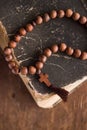 Wooden prayer beads with a Christian cross lie on the holy bible book on a wooden background. Royalty Free Stock Photo