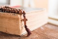 Wooden prayer beads with a Christian cross lie on the holy bible book on a wooden background. Royalty Free Stock Photo