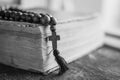 Wooden prayer beads with a Christian cross lie on the holy bible book on a wooden background. Royalty Free Stock Photo