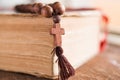 Wooden prayer beads with a Christian cross lie on the holy bible book on a wooden background. Royalty Free Stock Photo