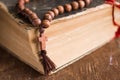 Wooden prayer beads with a Christian cross lie on the holy bible book on a wooden background. Royalty Free Stock Photo