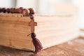 Wooden prayer beads with a Christian cross lie on the holy bible book on a wooden background. Royalty Free Stock Photo