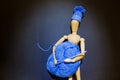 Wooden puppet doll holds a ball of blue yarn and crochet hook in its hands, and wears a knitted winter hat Royalty Free Stock Photo