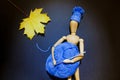 Wooden puppet doll holds a ball of blue yarn and crochet hook in its hands, and wears a knitted winter hat Royalty Free Stock Photo