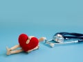 Wooden puppet hugging red heart and fall down on the floor in front stethoscope. copy space for text and content. concept Heart at Royalty Free Stock Photo