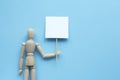 Wooden puppet human on blue background holding white banner