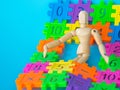 Wooden puppet sleep in colorfull plastic number on blue background. Concept of education mathematics or calculation. copy space