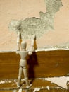 Wooden puppet tried to fix old Paint peeling plaster walls damage surface. A background of peeling paint, the old paint texture Royalty Free Stock Photo