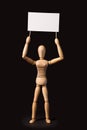 Wooden puppet with a poster or banner in their hands on a black Royalty Free Stock Photo