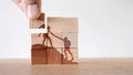 Wooden puzzle of climbers helping each other to reach the summit- concept of teamwork