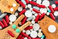 Wooden rabbit with green pill eyes and his friends bear and cat against background of many pills, pills and vitamins Royalty Free Stock Photo
