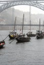 Wooden rabelos boats docked in the Douro River in Oporto, with barrels of wine, with the Don Luis I steel bridge in the background Royalty Free Stock Photo