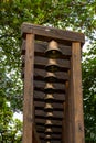 Wooden rack with many brass bells and trees behind