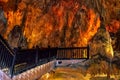 Wooden railing of a staircase against the background of orange-yellow fiery stone formations underground in Damlatas cave Alanya Royalty Free Stock Photo