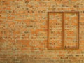 Wooden rectangular frame with a metal grill on the background of an old brick wall