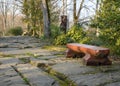 A wooden red bench on a path paved with huge stones covered with moss Royalty Free Stock Photo