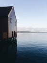 Wooden red house at the sea in Norway during sunset with a beautiful lake view