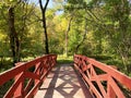 Wooden red nature river bridge walkway path glen sunshine hiking trail forest Royalty Free Stock Photo