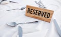 A wooden Reserved sign on a restaurant table with a white tablecloth