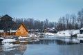 Wooden restaurant near the frozen pond in sunset, winter cloudy day Royalty Free Stock Photo