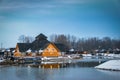 Wooden restaurant near the frozen pond in sunset, winter cloudy day Royalty Free Stock Photo