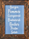 Wooden restaurant sign that reads Burger Pommes Currywurst Bratwurst Bockwurst Pasta Salad