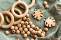 Wooden rings, beads and monstera clips for baby teether on green fabric. Natural wood toy for child. Eco-friendly toy.