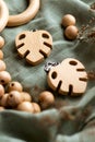 Wooden rings, beads and monstera clips for baby teether on green fabric. Natural wood toy for child. Eco-friendly toy.