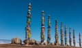 Wooden ritual pillars stand in a row against the blue sky.