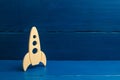 A wooden rocket on a blue background. The style is retro. The concept of space flights and achievements in high technologies. Busi