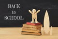 Wooden rocket with wooden dummy in front of classroom blackboard.