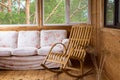 A wooden rocking chair and a sofa on the porch or terrace with a view of the forest. Royalty Free Stock Photo