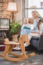 wooden rocking horse and happy family reading book behind 1950s Royalty Free Stock Photo