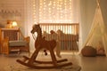 wooden rocking horse in a welllit nursery room with baby Royalty Free Stock Photo