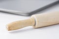 Wooden rolling pin and grey metal baking tray on white tabletop background. Clean minimalist modern styled image. Cooking, pastry,