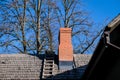 Wooden roof of a detached house with a skylight and red brick chimney against the sky Royalty Free Stock Photo