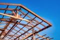 Wooden roof frame of a house against a blue sky. The frame of the cottage. The beginning of the construction of the house,