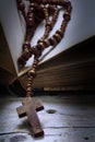 Wooden rosary beads with cross in an old book on rustic wood, re Royalty Free Stock Photo