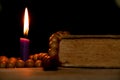 Wooden rosary and bible lie on a table near a candle in the dark, prayer and religion, god Royalty Free Stock Photo
