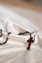 A wooden rosary with crucifix isolated on a beige colored fabric background Royalty Free Stock Photo