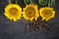 Wooden Rosary with Jesus Christ Cross Crucifix and three beautiful sunflwoers blossom arrangement on rustic table background.