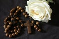 Wooden rosary with Jesus Christ holy cross crucifix and white rose on black background. Catholic rosary symbil Royalty Free Stock Photo