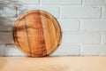 Wooden round board on orange table with shadow from palm tree with free space for inscription in a white brick wall Royalty Free Stock Photo