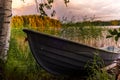 A wooden rowing boat at Sunset on the shores of the calm Saimaa lake in Finland under a nordic sky with a rainbow - 1 Royalty Free Stock Photo